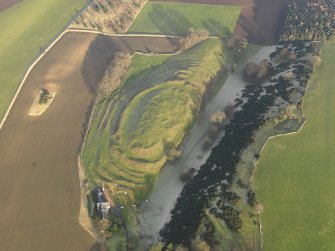 Oblique aerial view centred on the remains of the fort with the farmstead adjacent, taken from the SW.