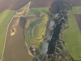 Oblique aerial view centred on the remains of the fort with the farmstead adjacent, taken from the WSW.