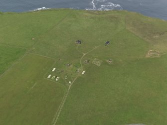 Oblique aerial view centred on the radar station with the chambered cairn adjacent, taken from the SSE.
