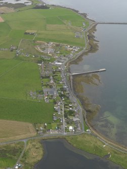 Oblique aerial view centred on the village with the pier adjacent, taken from the W.