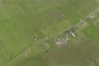 Oblique aerial view centred on the remains of the radar station remote reserve with farmsteads adjacent, taken from the NW.