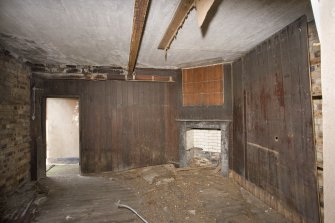 Interior, ground floor room with wooden lined walls and fireplace.