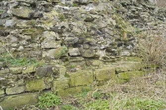 Detail of surviving section of 16th century wall showing rubble infilling and lower two course of faced blocks from SE.