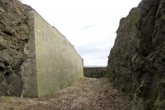 Interior, detail of south rock cut ditch with concrete revetting from the WSW.