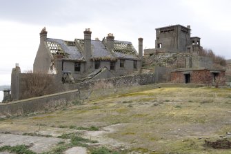 General view of the rear of the cottages from the water catchment area with the Port War Station in the background, from the ESE.