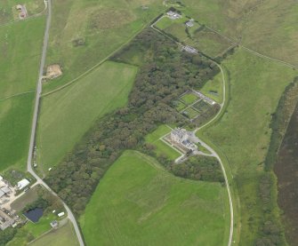 Oblique aerial view centred on the house and gardens with the remains of the chambered cairn adjacent, taken from the SE.