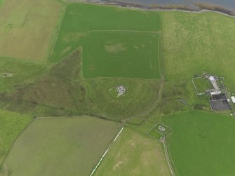 Oblique aerial view centred on the remains of the castle with the chapel and farm adjacent, taken from the SSE.