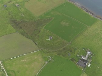 Oblique aerial view centred on the remains of Cubbie Roo's castle with the chapel and farm adjacent, taken from the ESE.