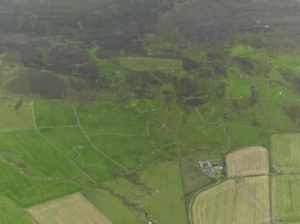 General oblique aerial view of the remains of the chambered cairn, farmsteads and fields at Knowe of Lingro on Rousay, taken from the NNE.