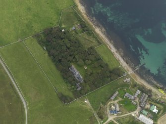 Oblique aerial view centred on the house with the remains of the chambered mound adjacaent, taken from the N.