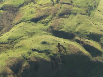 Oblique aerial view centred on the remains of the fort on Knock Scalbart with the quarries, enclosures and rig adjacent, taken from the NNW.