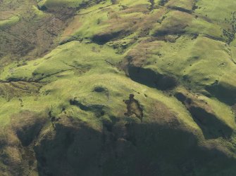 Oblique aerial view centred on the remains of the fort on Knock Scalbart with the quarries, enclosures and rig adjacent, taken from the NW.