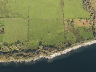General aerial oblique view centred on the remains of the chambered cairn, taken from the SW.