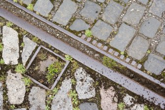 Detail of tram track with two directions of laid setts at W end of depot.