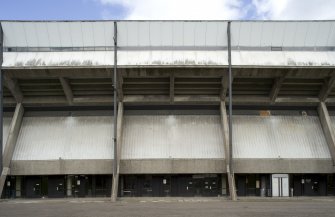 Detailed view of Meadowbank Stadium, Edinburgh, from the south, showing the exposed concrete structure of the grandstand and concrete panels to the concourse level.