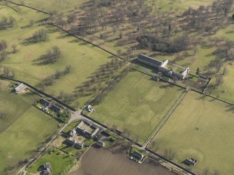 Oblique aerial view centred on the Riding Stables with the Home Farm adjacent, taken from the NW.