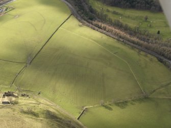 Oblique aerial view centred on the remains of rig and furrow cultivation with the remains of the tower house adjacent railway tunnel, taken from the NE.