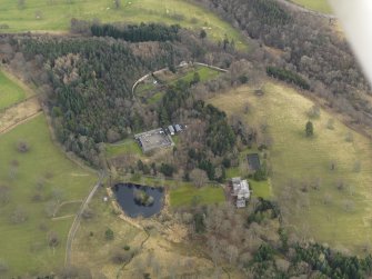 Oblique aerial view centred on the country house with the home farm and walled garden adjacent, taken from the  WSW.