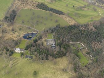 Oblique aerial view centred on the country house with the home farm and walled garden adjacent, taken from the SSE.