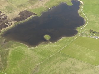Oblique aerial view centred on the ruins of a building and enclosure on an island in Loch of Wasdale, taken from the SE.