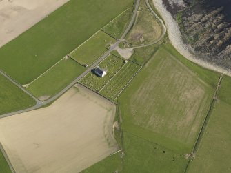 Oblique aerial view centred on St Peter's Kirk and burial ground, taken from the NW.