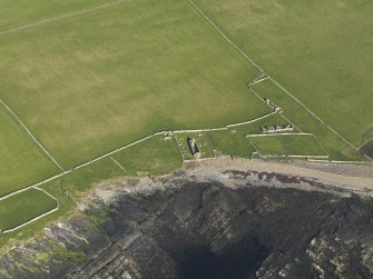 Oblique aerial view centred on St Mary's Church, Westside, with the remains of The Wirk tower house to the top left of the burial ground, taken from the W.