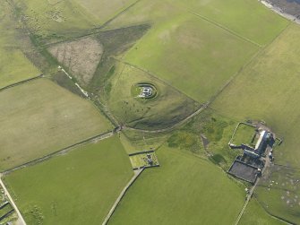 Oblique aerial view centred on Cubbie Roo's Castle with St Mary's Chapel and The Bu farmstead adjacent, taken from the E.