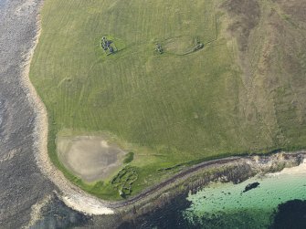 Oblique aerial view centred on a farmstead on Eynhallow with the monastery and rig and furrow adjacent, taken from the SE.