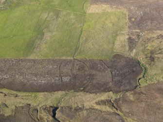 Oblique aerial view centred on the remains of the round house, enclosures, banks and a trackway on Peerie Hill, taken from the SSW.
