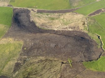 Oblique aerial view centred on the remains of the round house, enclosure and field banks on the summit of Billia Fiold, taken from the SW.
