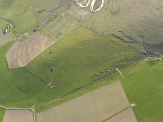 Oblique aerial view centred on the ruins of the farmstead and the field boundaries at Hill of Borwick with the remains of a firing range adjacent, taken from the NE.