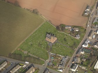 Oblique aerial view of the church with the churchyard adjacent, taken from the SW.