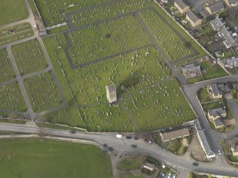 Oblique aerial view centred on the remains of the church with the graveyard adjacent, taken from the S.