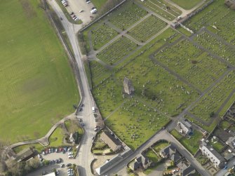 Oblique aerial view centred on the remains of the church with the graveyard adjacent, taken from the  ESE.