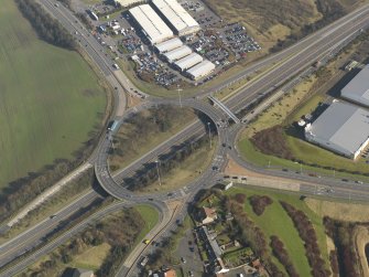 Oblique aerial view centred on the motorway interchange, taken from the NW.