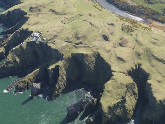 General oblique aerial view of the defended promontary and possible nunnery with St Abb's Head Lighthouse adjacent, taken from the NNW.