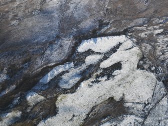 Oblique aerial view centred on the remains of the building, field banks and rig and furrow, taken from the N.