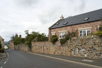 General view from SE showing lower courses of earlier cottage with new house in the background.