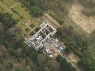 Oblique aerial view centred on the fire damaged house, taken from the NW.