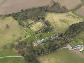 Oblique aerial view centred on the country house with the stable block and walled garden adjacent, taken from the NNE.