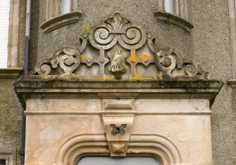 Detail of ornate carved main entrance door pediment with 'owl' motif and nailhead decoration.