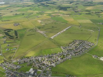 General oblique aerial view centred on the airfield with the village adjacent, taken from the N.
