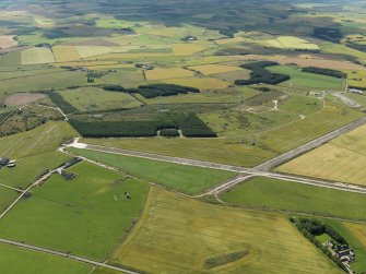 General oblique aerial view centred on the remains of the airfield with the windfarm adjacent, taken from the N.