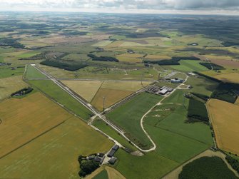General oblique aerial view centred on the remains of the airfield with the windfarm adjacent, taken from the NW.
