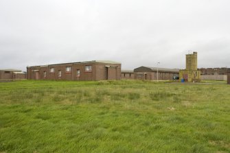 View from SW of single quarters for officers with a boiler house in the background.