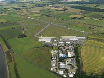 Oblique aerial view centred on the technical site (terminal area) with the airfield adjacent, taken from the WNW.