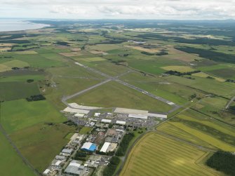 General oblique aerial view centred on the airfield with the technical site (terminal area) adjacent, taken from the W.