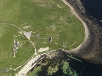 Oblique aerial view centred on the church, burial ground and fishing station at Kirkhouse Bay, taken from the SW.