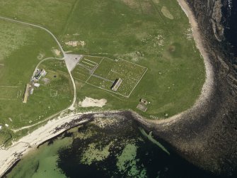 Oblique aerial view centred on the church, burial ground and fishing station at Kirkhouse Bay, taken from the SW.