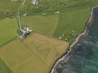 Oblique aerial view centered on the cropmarks of the infilled stream gullies with Northfield battery, West of Burray broch and Northfield farmstead adjacent, taken from the NE.